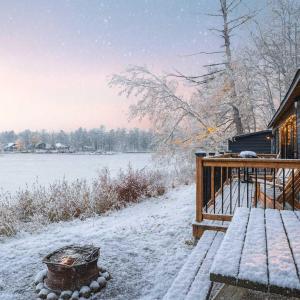 a snow covered porch of a house next to a lake at 2-Bedroom Cottage #11 - Red Pine in Gravenhurst