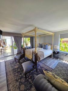 Hermanus Manor في هيرمانوس: غرفة نوم مع سرير بمظلة وكرسيين