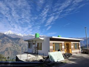 a small white house with mountains in the background at Dadi Homestay in Munsyari