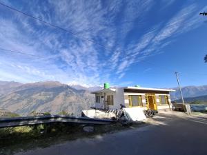 a small white house with mountains in the background at Dadi Homestay in Munsyari