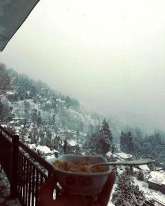 a person holding a bowl of food in the snow at Dadi Homestay in Munsyari