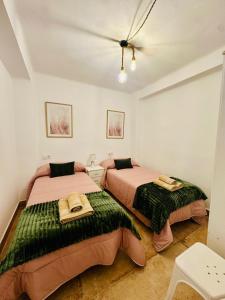 a bedroom with two beds with green blankets at Arenas del Coliseo Parking Gratis in Merida