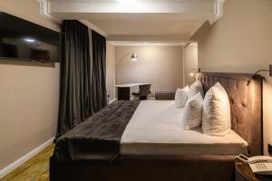 a hotel room with a large bed with white pillows at Hotel Brilliant Plaza in Zalău