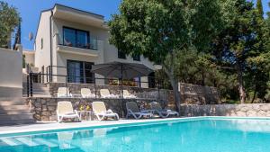 a swimming pool with chairs and an umbrella next to a house at Villa Tea - Kremena by Villas Guide in Blace