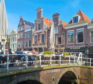 Eine Brücke über einen Kanal, auf der Menschen an Tischen sitzen. in der Unterkunft Slapen bij De Buren in Alkmaar