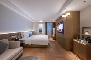 ein Hotelzimmer mit Bett und Fernseher in der Unterkunft Manxin Hotel Wuhan Jianghan Road Pedestrian Street in Wuhan