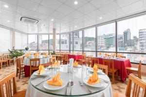 a dining room with tables and chairs and windows at Thai Ha Hotel in Ha Long