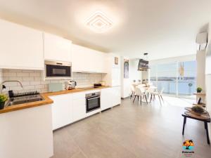 a kitchen with white cabinets and a table with chairs at El Dorado in Arguineguín +6 photos