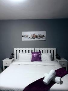 una camera da letto con un grande letto bianco con cuscini viola di Ngwanase Properties a Durban