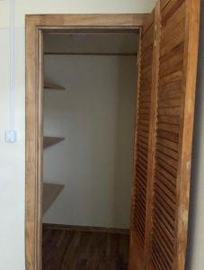 a closet with a wooden door and shelves at Cabaña Quellón 