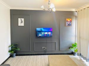 - un salon avec une télévision sur un mur gris dans l'établissement Zuri stays, à Kampala