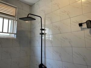 La salle de bains est pourvue d'une douche et d'un mur en marbre. dans l'établissement Zuri stays, à Kampala