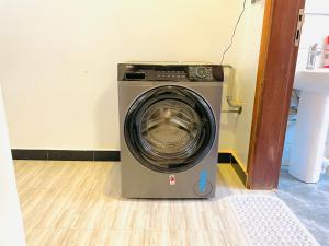 une machine à laver posée dans le coin d'une pièce dans l'établissement Zuri stays, à Kampala