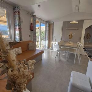 L'Oasis Mobil Home à 100m de la Plage Camping 5 étoiles في توراي: غرفة معيشة مع أريكة وطاولة