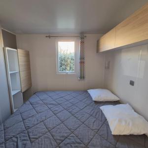 L'Oasis Mobil Home à 100m de la Plage Camping 5 étoiles في توراي: غرفة نوم بسرير كبير ونافذة