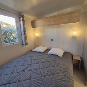 L'Oasis Mobil Home à 100m de la Plage Camping 5 étoiles في توراي: غرفة نوم بسرير كبير ونافذة