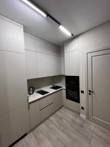 an empty kitchen with white cabinets and a door at Инжу Сити in Karagandy