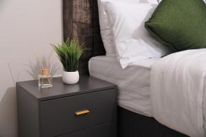 a nightstand with a plant on it next to a bed at Sentlhaga 1 Bed Self Catering Apartment, Sarona City,Habitat Kappa, Gaborone in Gaborone