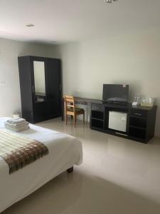 a bedroom with a bed and a desk with a television at บ้านทรัพย์มงคล in Ban Nua Khlong