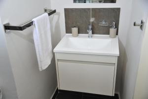 a bathroom with a white sink and a towel at Sentlhaga 1 Bed Self Catering Apartment, Sarona City,Habitat Kappa, Gaborone in Gaborone