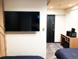 a hotel room with a flat screen tv on the wall at HOTEL LiVEMAX BUDGET Iyo Mishima in Shikokuchuo