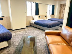 a hotel room with two beds and a couch at HOTEL LiVEMAX BUDGET Iyo Mishima in Shikokuchuo