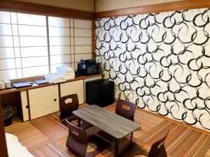 a room with a table and chairs and a wall at HOTEL LiVEMAX BUDGET Iyo Mishima in Shikokuchuo
