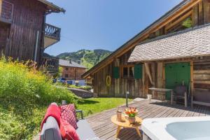a wooden deck with a bath tub next to a building at La Ferme a Mamy - Snowytrees in Morzine