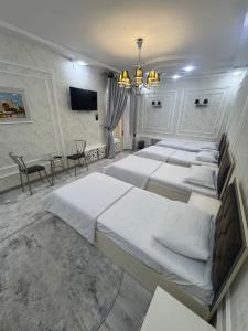 a group of beds in a room with a table at Abubakir Guests House in Samarkand