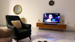 a living room with a flat screen tv and a chair at Le Prestige Appartement à Oloumi in Libreville +21 photos