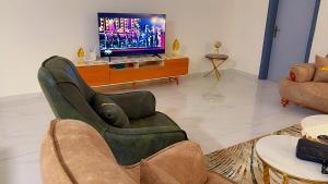 a living room with two chairs and a flat screen tv at Le Prestige Appartement à Oloumi in Libreville