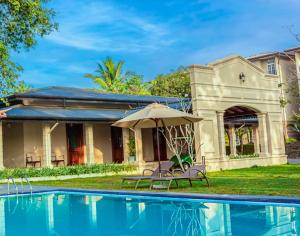 una casa con piscina y sombrilla en The Palace Gampaha by Axendra, en Gampaha