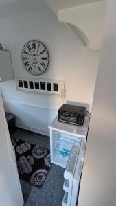 a clock on the wall above a small refrigerator at Ferienwohnung Bergstraße Hammermühle in Bad Düben