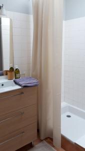 a bathroom with a shower curtain and a sink and a tub at Maisonnette l'Olivier Bleu in Nantes