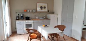 a kitchen with a white table and chairs and a table and a white table at Maisonnette l'Olivier Bleu in Nantes