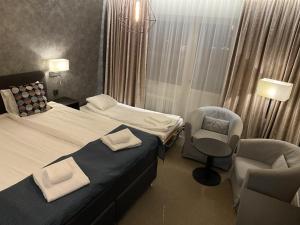 a hotel room with two beds and two chairs at Hotell Rättvik in Rättvik