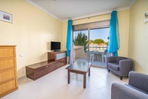 een woonkamer met een tv, een bank en een tafel bij Apartamentos Vista Mar in Armação de Pêra