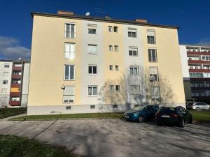 Un edificio grande con dos coches estacionados en un estacionamiento. en Charmante 2-Zimmer-Wohnung, en Eisenstadt