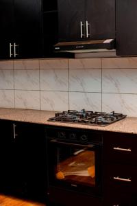a stove top oven in a kitchen with black cabinets at Happy Home House in Ruhengeri