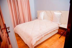 a bedroom with a bed with a white comforter at Happy Home House in Ruhengeri
