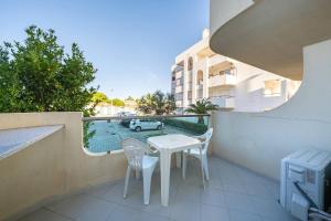 een balkon met een witte tafel en stoelen en een auto bij Apartamentos Vista Mar in Armação de Pêra