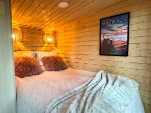 a bedroom with a bed in a wooden wall at Lapland Landscape Cabin with Nature View, Sauna, Fireplace & Kitchen, Ylläs, Äkäslompolo, Borealis Village in Äkäslompolo