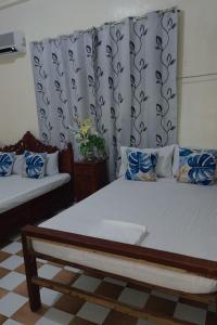 a bedroom with two beds with blue and white pillows at Besañes Homestay in Alaminos +30 photos