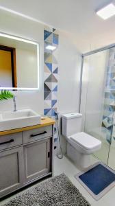 a bathroom with a sink and a toilet and a mirror at Casa das Dunas in Garopaba