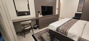 a bedroom with a bed and a desk with a television at Modern Omani Inspired Apartment in Muscat in Muscat