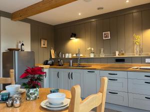 a kitchen with a table with chairs and a refrigerator at Award Winning Lodge at Ewen Barn, Ewen, Cirencester in Cirencester