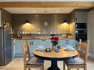 a kitchen with a table and chairs and a refrigerator at Award Winning Lodge at Ewen Barn, Ewen, Cirencester in Cirencester
