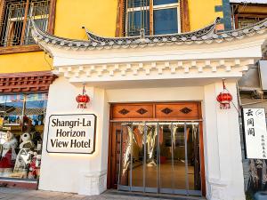 香格里拉Shangri La Horizon View Hotel Dukezong Ancient City Branch located near the prayer wheel of the Great Buddha Temple, offers free high-speed train plane pick-up upon check-in的一家商店的店面，旁边是一座中国式建筑。