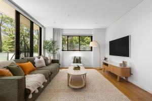 ein Wohnzimmer mit Sofa und Tisch in der Unterkunft Upper North Shore Haven - A Tranquil Treetop Escape in Warrawee