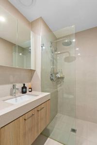 ein Badezimmer mit Waschbecken und Glasdusche in der Unterkunft Upper North Shore Haven - A Tranquil Treetop Escape in Warrawee